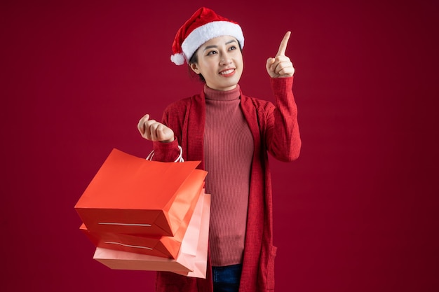 Giovane donna asiatica che indossa il cappello di Natale su sfondo rosso