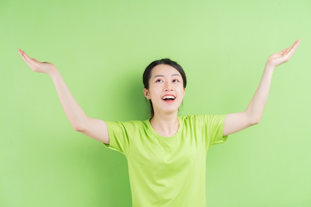 Giovane donna asiatica che indossa una maglietta verde e posa su sfondo verde