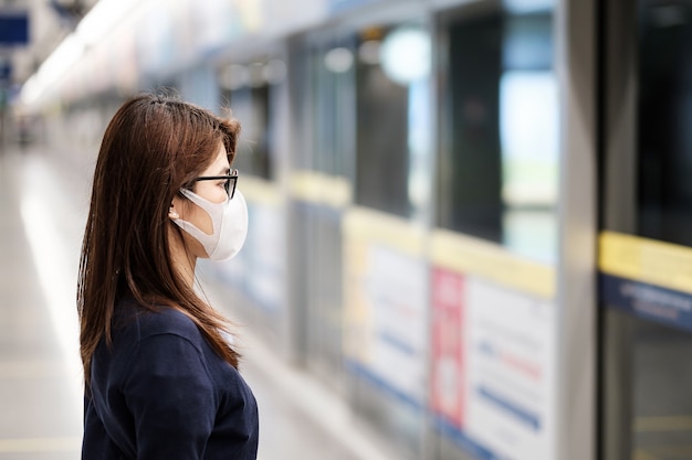 Giovane donna asiatica che indossa una maschera di protezione contro il romanzo coronavirus o Corona Virus Disease (Covid-19) all'aeroporto