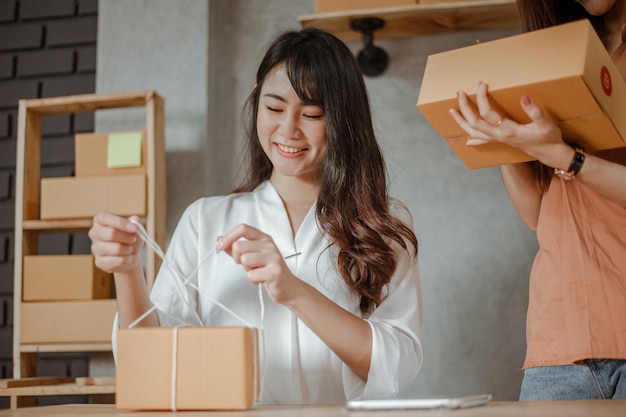 Giovane donna asiatica che lavora da casa marketing online imballaggio e consegna per il cliente a casa. Imprenditore, PMI, spedizione, lavoro da casa (WFH), freelance, concetto di avvio.