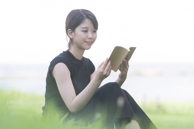 Giovane donna asiatica che legge un libro nel parco