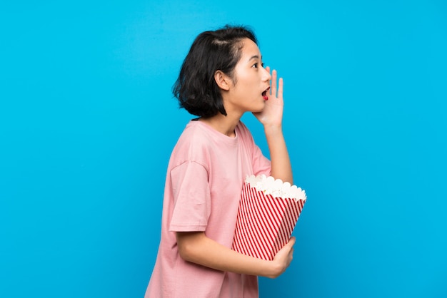 Giovane donna asiatica che mangia i popcorn