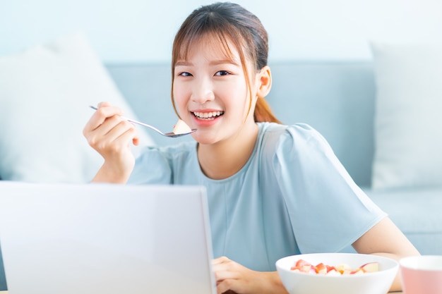 Giovane donna asiatica che mangia prima colazione e selfie nel suo salotto