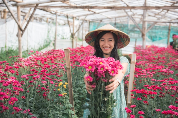 Giovane donna asiatica che mostra i fiori della camomilla