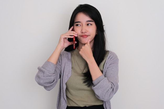 Giovane donna asiatica che pensa a qualcosa quando risponde a una telefonata