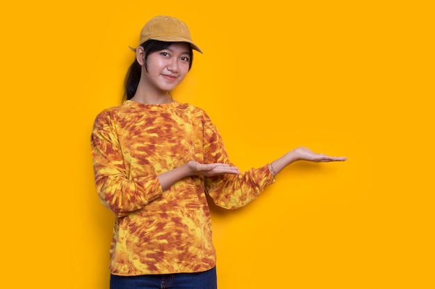giovane donna asiatica che punta con le dita in direzioni diverse isolate su sfondo giallo