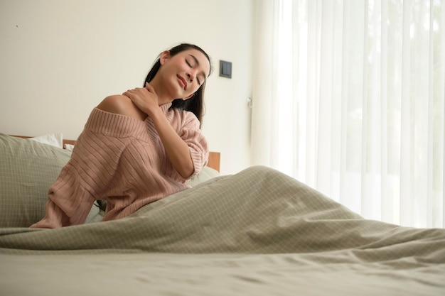 Giovane donna asiatica che si allunga nel letto dopo essersi svegliata al mattino