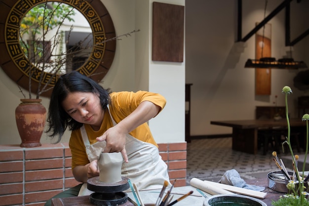 Giovane donna asiatica che si concentra sul suo lavoro presso il laboratorio di ceramica