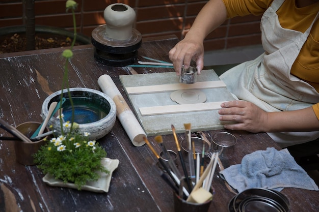 Giovane donna asiatica che si concentra sul suo lavoro presso il laboratorio di ceramica