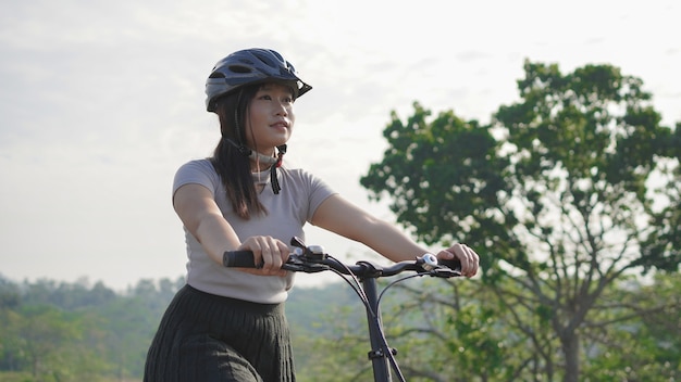 Giovane donna asiatica che si diverte in bicicletta nella mattina d'estate