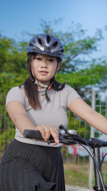 Giovane donna asiatica che si gode il ciclismo quando si ferma nella mattinata estiva