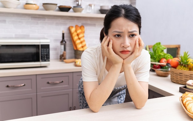 Giovane donna asiatica che si sente stanca dei lavori domesticixA