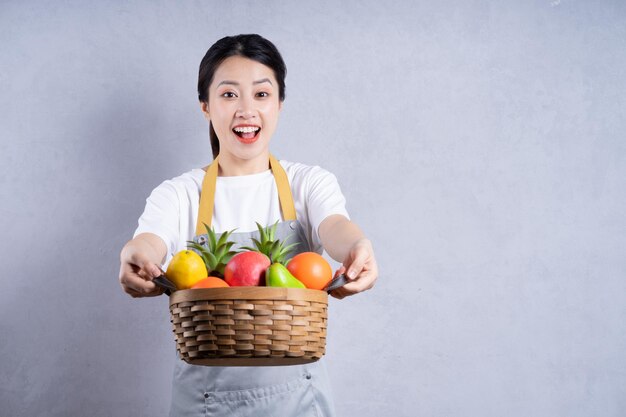 Giovane donna asiatica che tiene le verdure sullo sfondo