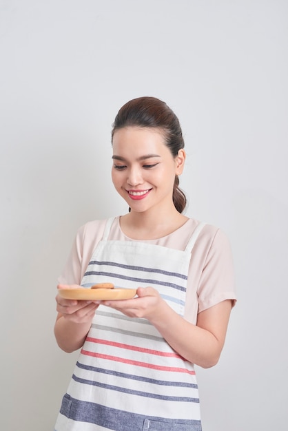 Giovane donna asiatica che tiene piatto con biscotti al cioccolato fatti in casa