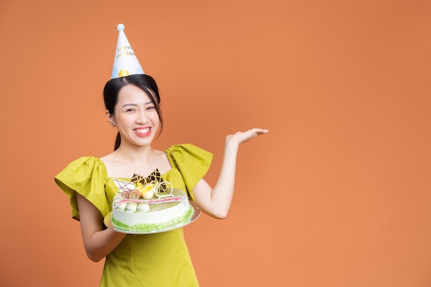 Giovane donna asiatica che tiene torta di compleanno