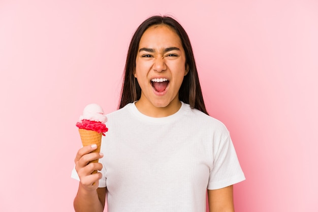 Giovane donna asiatica che tiene un gelato isolato che grida molto arrabbiato e aggressivo.