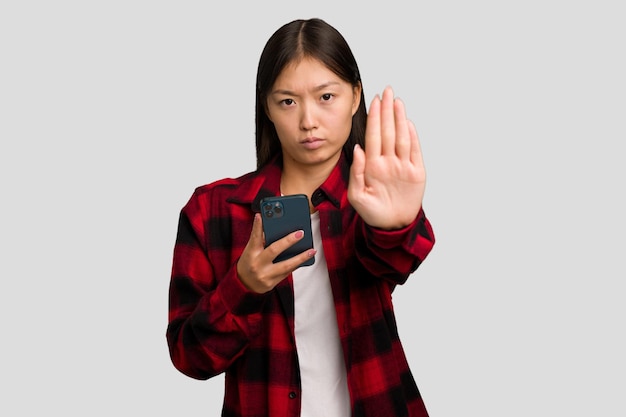 Giovane donna asiatica che tiene un telefono cellulare isolato