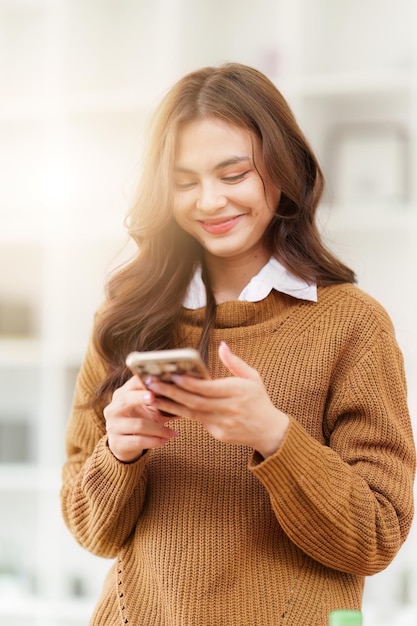 Giovane donna asiatica che usa lo smartphone a casa Cellulare femminile che tiene il controllo della posta elettronica o dei social media su internet