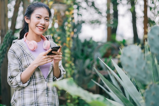 Giovane donna asiatica che utilizza smartphone in giardino