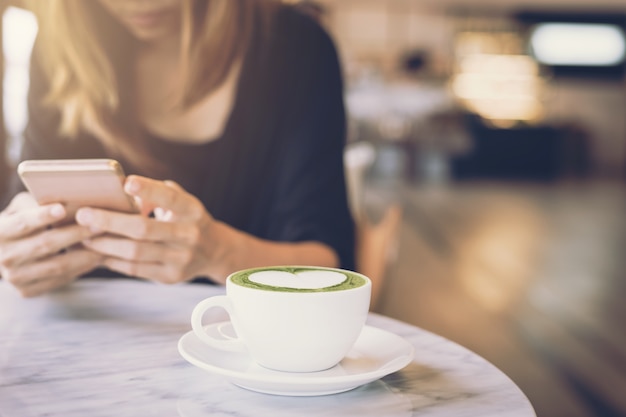 Giovane donna asiatica che utilizza telefono cellulare e che manda un sms nella rete sociale