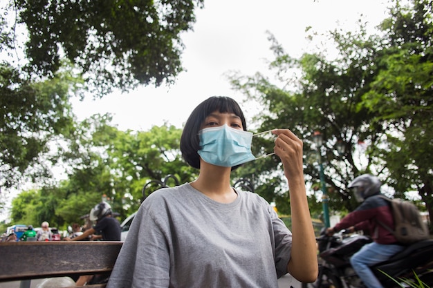 Giovane donna asiatica con maschera facciale negli spazi pubblici Concetto del virus Corona