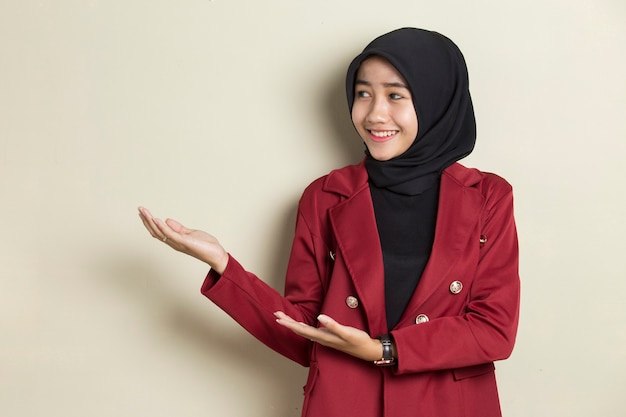 Giovane donna asiatica di affari che indossa il hijab sorridente fiducioso che punta con le dita in direzioni diverse.