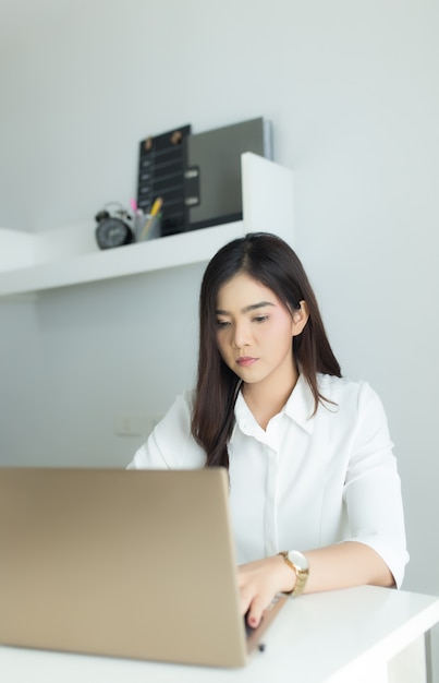 Giovane donna asiatica di affari che lavora al suo computer portatile sul posto di lavoro.