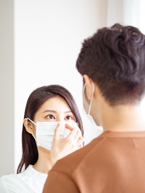 Giovane donna asiatica e uomo che indossa una maschera chirurgica a casa