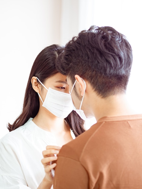 Giovane donna asiatica e uomo che indossa una maschera chirurgica a casa