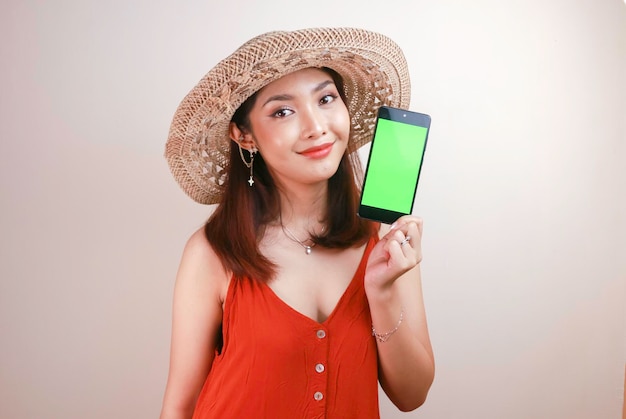 Giovane donna asiatica eccitata e sorridente che mostra lo schermo verde sullo smartphone in mano