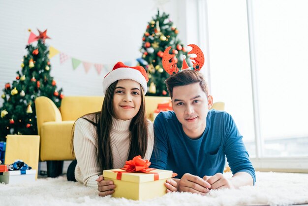 Giovane donna asiatica felice che indossa un cappello di Babbo Natale con il suo ragazzo con un regalo di Natale