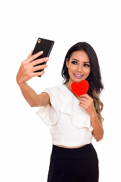 giovane donna asiatica felice innamorata che tiene il cuore e scattare foto selfie con il telefono