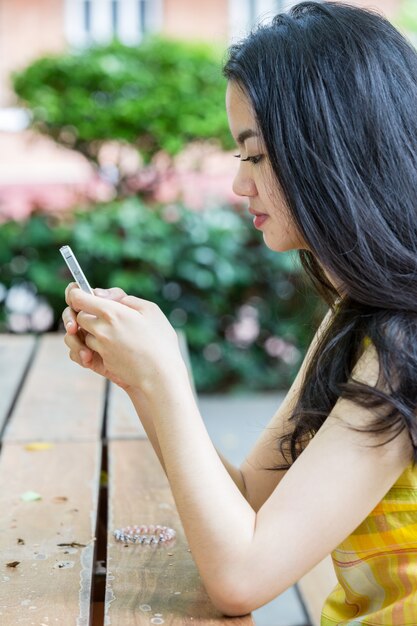 Giovane donna asiatica felicemente usando uno smart phone