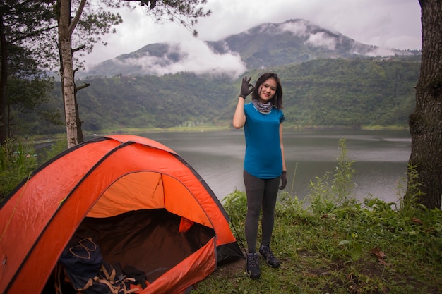 Giovane donna asiatica in campeggio o picnic nel lago della foresta.