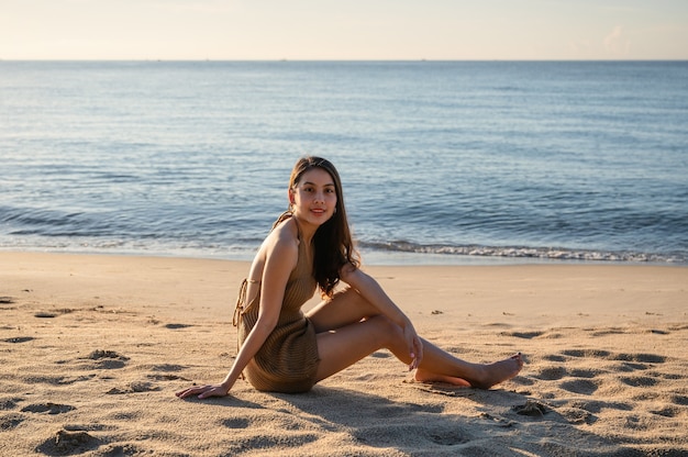 Giovane donna asiatica in costume da bagno rilassante e prendere il sole sulla spiaggia con il sole al mattino