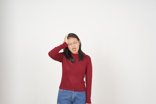 Giovane donna asiatica in maglietta rossa che soffre di mal di testa, gesto isolato su sfondo bianco