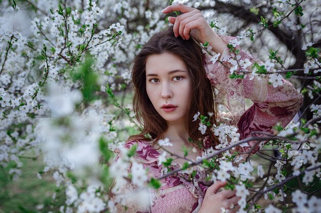 Giovane donna asiatica in un giardino fiorito. immagine romantica di donna casual elegante, camicetta di seta alla moda. umore positivo. Cheery Blossom piena fioritura in Giappone.