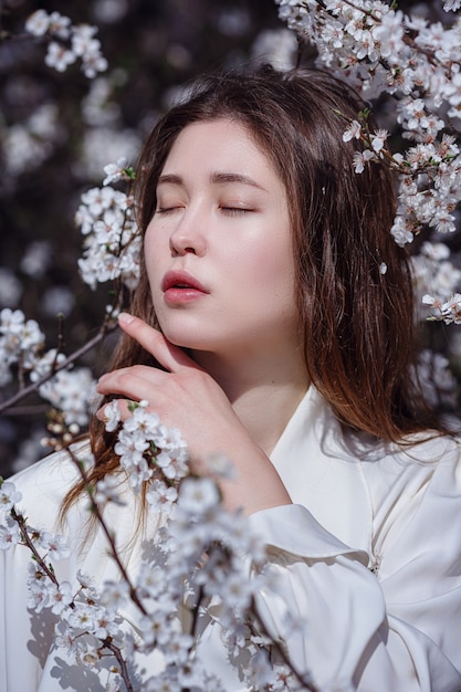 Giovane donna asiatica in un giardino fiorito. immagine romantica di donna casual elegante, camicetta di seta alla moda. umore positivo. Cheery Blossom piena fioritura in Giappone.