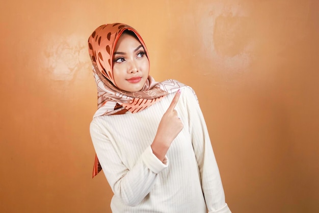 Giovane donna asiatica musulmana allegra che punta sopra per copiare lo spazio con un sorriso