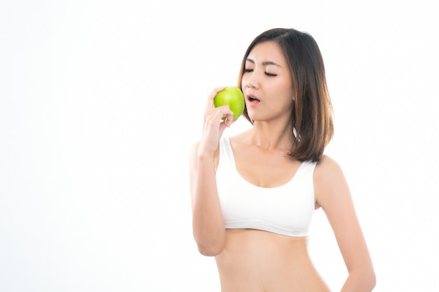 Giovane donna asiatica nel reggiseno bianco di sport che mangia mela verde.