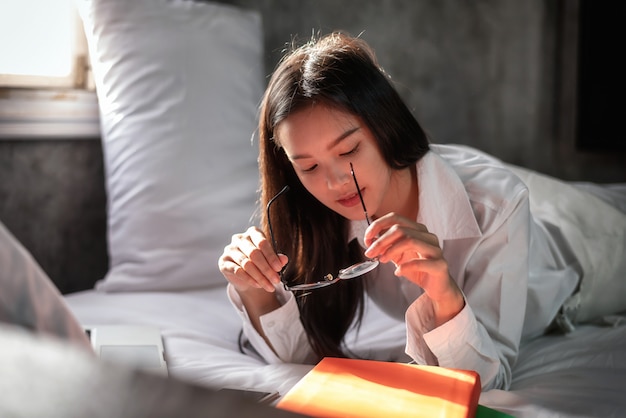 Giovane donna asiatica nella lettura di un libro sul letto