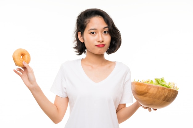 Giovane donna asiatica più isolata con insalata e ciambella
