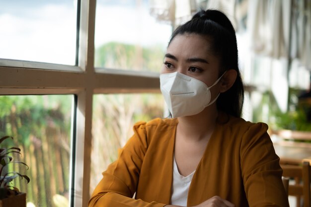 Giovane donna asiatica seduta e che indossa una maschera medica