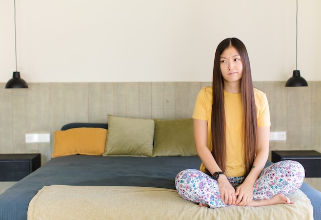 Giovane donna asiatica seduta sul letto