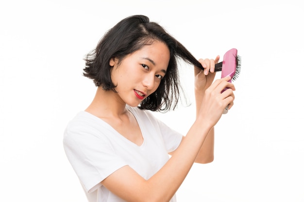Giovane donna asiatica sopra isolata con il pettine dei capelli