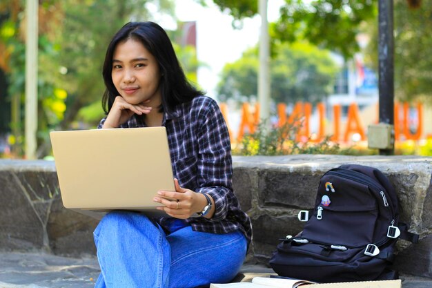 giovane donna asiatica sorridente che utilizza un laptop e scrive un notebook allegro studente asiatico che guarda il webinar