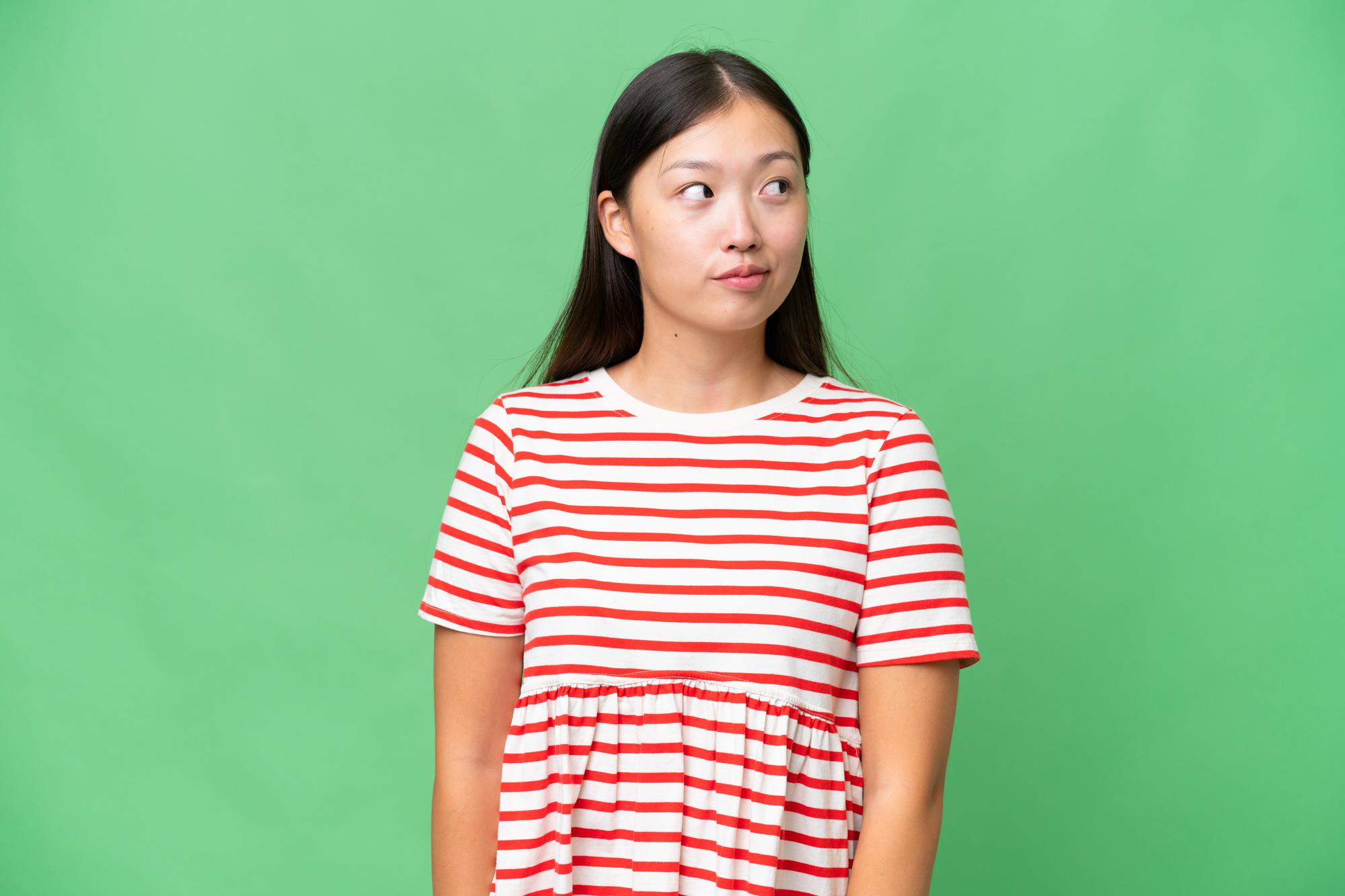 Giovane donna asiatica su sfondo isolato pensando un'idea durante la ricerca