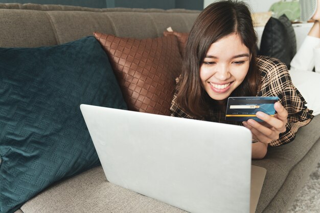 Giovane donna asiatica utilizzando la carta di credito per lo shopping online