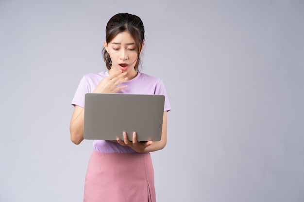 Giovane donna asiatica utilizzando laptop su grigio