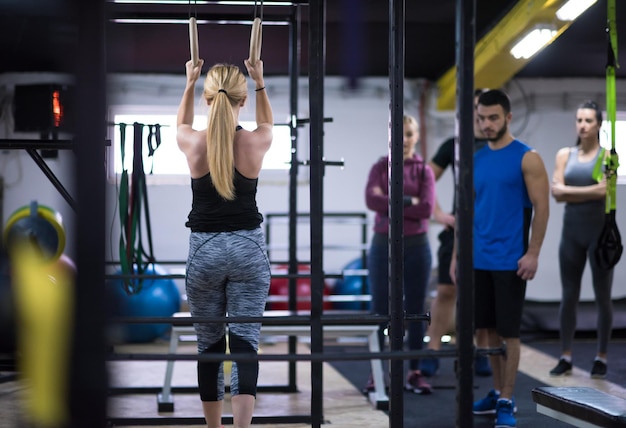 giovane donna atletica che lavora con personal trainer su anelli di ginnastica presso la palestra cross fitness